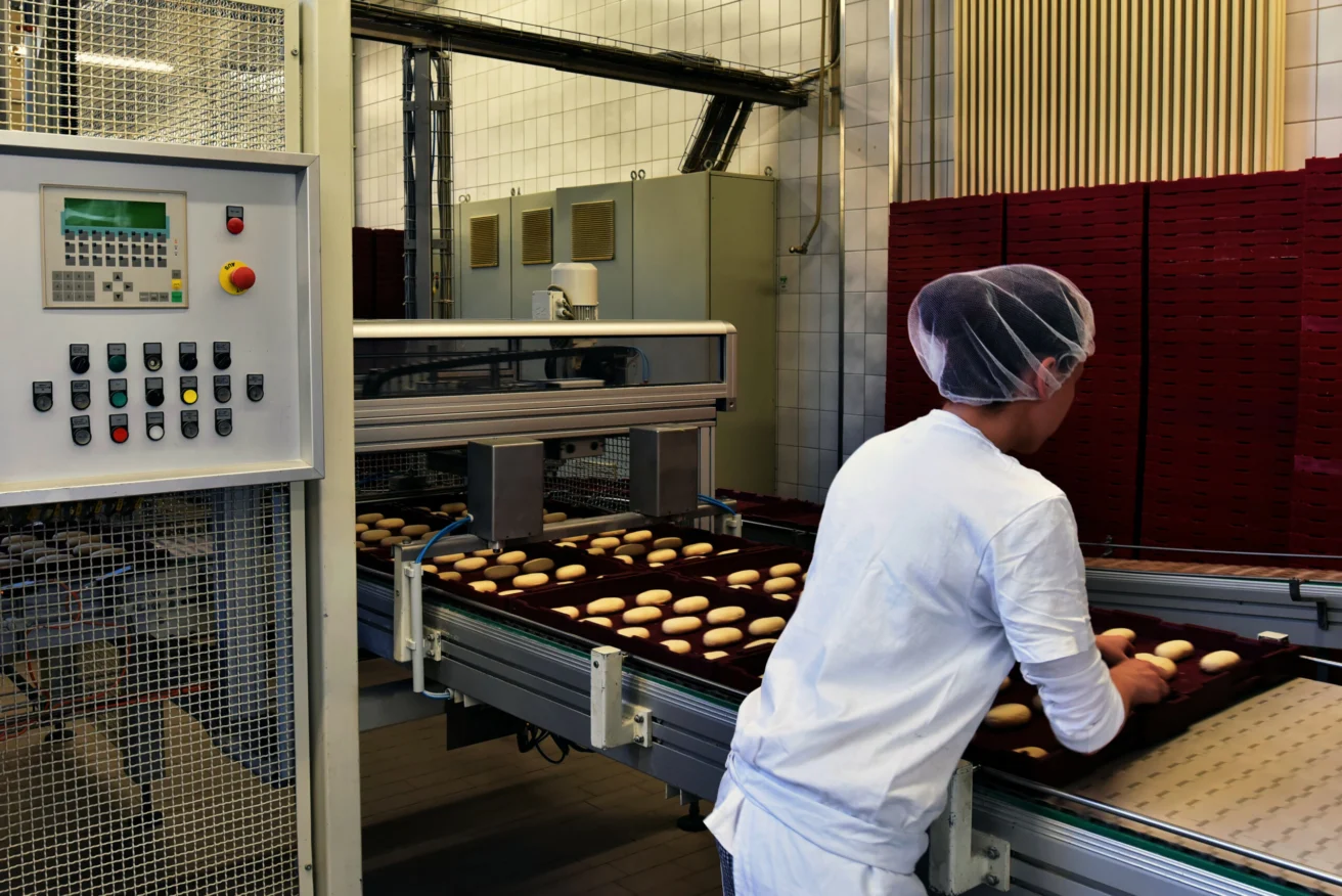 Woman working on the conveyor belt of a bakery