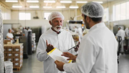 Two serious business men in sterile clothing standing in a food manufacturing factory.